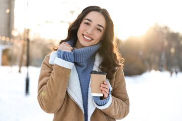 Canvas Print - Portrait of smiling woman with paper cup of coffee in snowy park