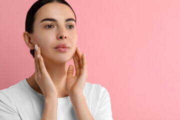 Poster - Woman with dry skin checking her face on pink background, space for text