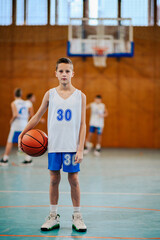 Sticker - Portrait of a boy with a basketball on court during the training.