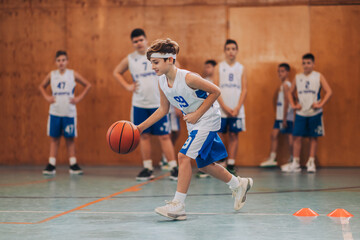 Poster - A junior basketball player dribbling a ball and practicing on court.