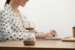© New Africa - Hourglass with flowing sand on desk. Woman taking notes while using calculator indoors, selective focus