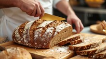 Whole Grain Bread Put On Kitchen Wood Plate With A Chef Holding Gold Knife For Cut. Fresh Bread On Table Close-up. Fresh Bread On The Kitchen Table The Healthy Eating And Traditional Bakery Concept