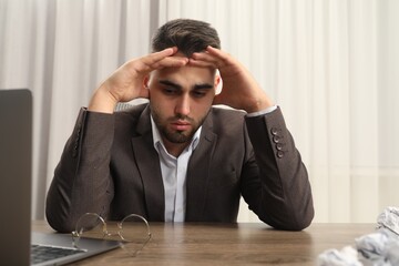 Wall Mural - Tired sad businessman sitting at table in office