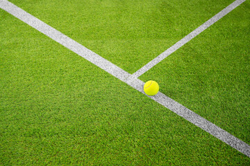 Wall Mural - Closeup of one yellow tennis ball or paddle tennis and white lines on green court. Horizontal sport poster, greeting cards, headers, website