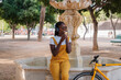 Young woman in yellow overalls eating ice cream in the city square.