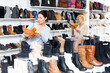 © JackF - Focused Asian woman attentive chooses winter boots with fur in a shoe store