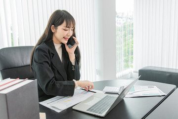 Wall Mural - woman talking on the mobile phone and smiling while sitting at her working place in office.