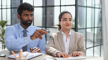 Young indian mentor coach talking with female colleague teaching trainee having business conversation with work colleague