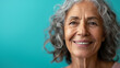 a happy gray haired ethnic elderly woman with a beautiful white smile on blue background. stock photo