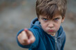 怒りの表情の小さな男の子が指を指して反抗している。