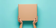 Top View To Female Hand Holding Brown Cardboard Box On Light Blue Background. Mockup Parcel Box. Packaging, Shopping, Delivery Concept