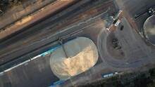 Corn, Grain And Pipeline Showing Heap Of Cereal At Sunny Day. Grain Cargo Truck Unloading Grain In Grid. Aerial Top Down.