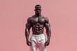 © robertuzhbt89 - Muscular man posing confidently against a pink background, showcasing fitness and strength.