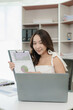 © MrAshi - Young Asian woman working using a laptop computer, doing accounting analysis, reporting real estate investment data. Finance and tax system concepts, work at home concept