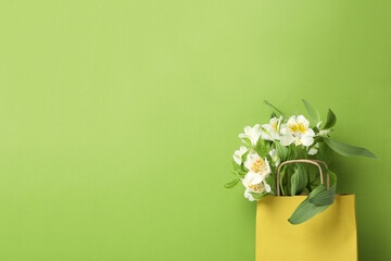 Wall Mural - Paper bag for shopping with flowers, on a green background.