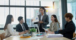 © SOMKID - Team of asian business working with document paper sitting at desk in office in meeting room, Business team working with project statistics, Asian business team and present graphic info in room.