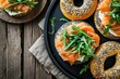 High angle view of a poppy seeds bagel spread with cheese cream and with smoked salmon and arugula topping on a rustic wooden table. 