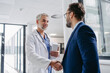 © Halfpoint - Pharmaceutical sales representative presenting new medication to doctor in medical building, shaking hands.