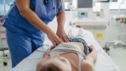 Close up of doctor palpating girl's abdomen, hands and steady pressure on belly. Concept of preventive health care for children.