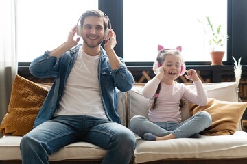 Wall Mural - Happy man and his little daughter listening to music at home.