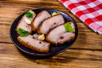 Wall Mural - Slices of baked pork belly, garlic and parsley on a black plate