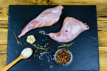 Wall Mural - Rabbit meat with pepper, rosemary, salt and garlic on a slate board. Top view