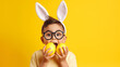 funny happy child boy with easter eggs and bunny ears on yellow background 