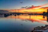 Fototapeta  - Sunrise with colourful cloud reflections and boats on the bay at Koolewong, NSW, Australia.