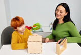 Fototapeta Tulipany - Child development specialist woman working with child with autism spectrum disorder. Play-based therapy
