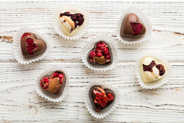 Poster - chocolate sweets in the form of a heart with fruits and nuts on a colored background. top view with space for text, holiday concept