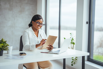 Wall Mural - Young businesswoman using a digital tablet and laptop in a modern office. Shot of a young businesswoman using a digital tablet while at work. The better connected, the easier the workflow