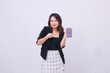 © Ajab - beautiful Indonesian office girl 20s smile expression promotion cellphone gadget screen for promo while pointing at it underneath isolated white background