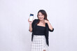 © Ajab - charm of beautiful Asian office woman 20s cheerful smile expression pointing right cellphone gadget for promo while arms crossed isolated white background