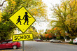 © Austockphoto - Bright yellow school sign in Autumn street with parked cars