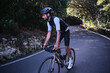 © KatyaPulka - A male cyclist is riding a bicycle on asphalt forest road in Anaga Park. Tenerife, Canary Islands. Effortful cycling mood. Cycle in beautiful nature. Man cyclist wearing cycling kit and helmet. Spain