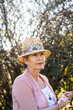 © Austockphoto - Senior woman wearing a hat in the garden looking to the side