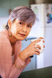 © Austockphoto - Middle aged woman drinking a cup of tea in her kitchen