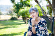 © Austockphoto - Mature aged woman relaxing in backyard under shady tree