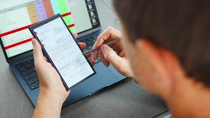 Close up view of man hand holding smart phone and stylus pen at his creative workspace. 