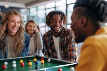 A diverse group of friends in stylish clothing gather around a pool table in an indoor recreation room, smiling and having fun as they play a tabletop game with balls and cues