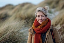 A Stylish Woman Braves The Winter Chill With A Warm Coat And Scarf, Her Face Beaming With A Content Smile Against The Backdrop Of The Sky And Grass