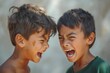 Two young boys, with smiles stretched wide and teeth bared, stand outdoors, their cheeks flushed with emotion as they passionately scream at each other, their clothing and skin reflecting the intensi