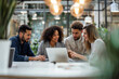 © ADDICTIVE STOCK - Group of People Sitting at a Table, Looking at a Laptop in a Business Meeting