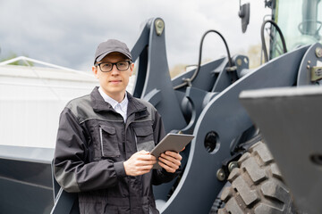 Poster - Serviceman with digital tablet on a background of the tractor.