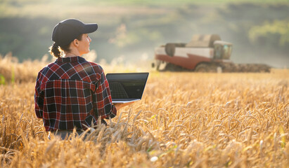 Poster - Woman farmer with digital tablet on a background of harvester. Smart farming concept