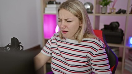 Sticker - Tired young blonde streamer, looking sleepily at her computer in her gaming room. exhausted from the fatigue of a hangover, her lazy eyes struggle against the morning