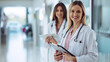 © MP Studio - smiling female healthcare professional in the foreground holding a clipboard with a stethoscope around her neck