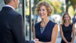 © Studio Nova - smiling young woman with brown hair in a white blouse, extending her hand for a handshake in a professional office environment