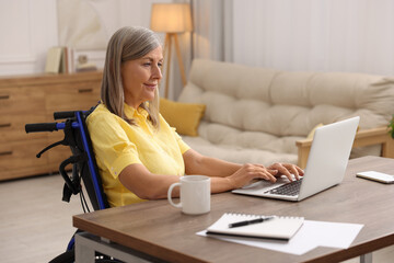 Poster - Woman in wheelchair using laptop at table in home office