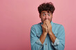 Nervous Latin man and biting nails in studio with oops reaction on pink background. Mistake, sorry, drama or secret with regret, shame or awkward